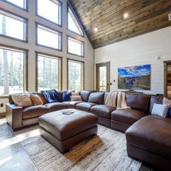 Leather sectional under tall windows looking out at the pines