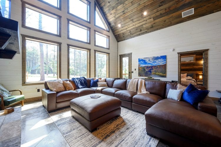 Leather sectional under tall windows looking out at the pines