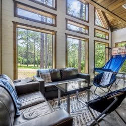 Black leather couch under a window looking at the pines
