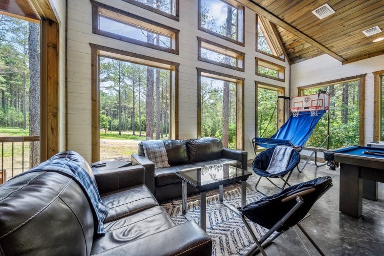 Black leather couch under a window looking at the pines