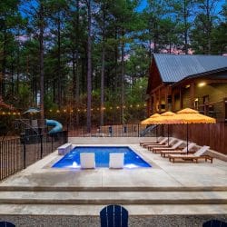 Pool edge with a black safety fence, string lights and a slide behind it
