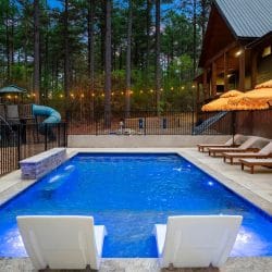 Pool behind a black fence with a seating area in the trees beyond