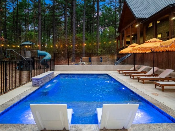 Pool behind a black fence with a seating area in the trees beyond