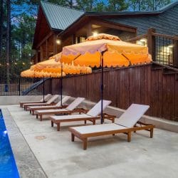 White loungers and umbrellas along a wood privacy fence