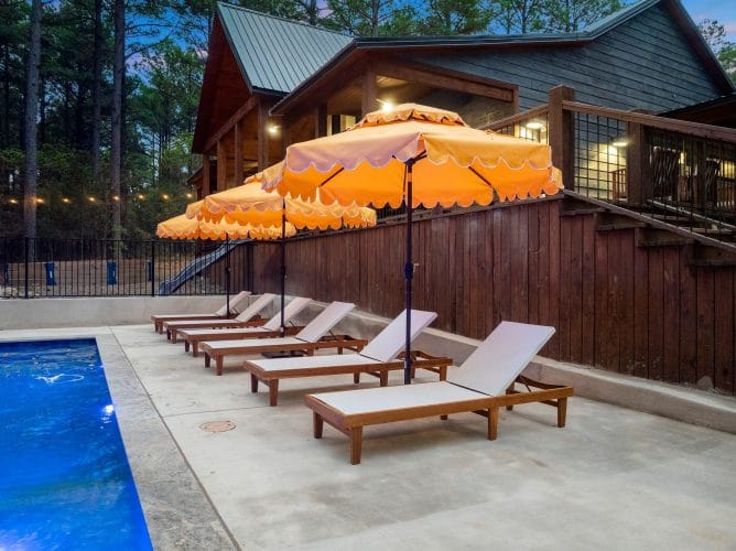 White loungers and umbrellas along a wood privacy fence