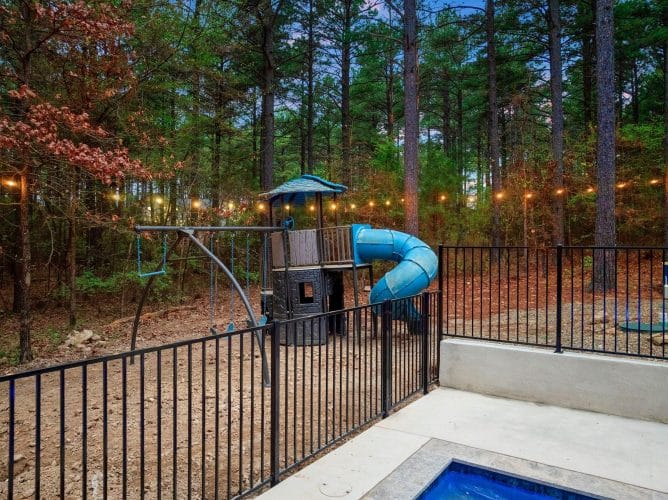 Kids playset with a blue spiral slide under string lights