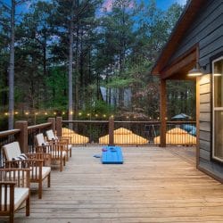 String lights and umbrellas along the deck railing with a rooftop peak in the trees