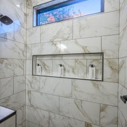 Shower niche with three pump bottles in marble-look tile