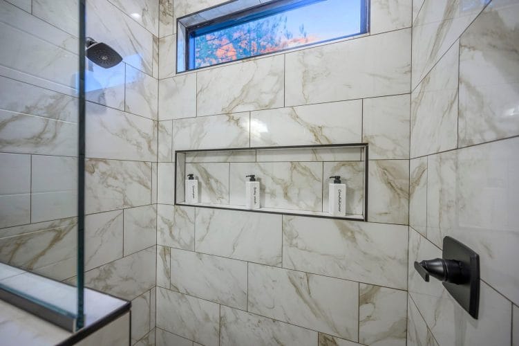 Shower niche with three pump bottles in marble-look tile
