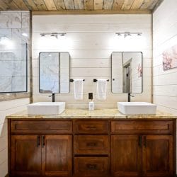 Double vessel sinks with white towels on bars and a granite counter