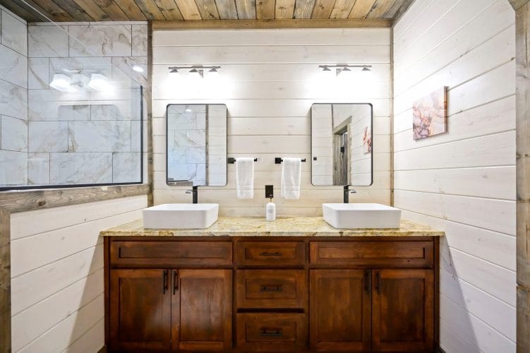 Double vessel sinks with white towels on bars and a granite counter