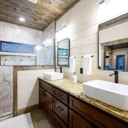 Vessel sink with a window into the shower and hanging white towels