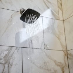 Water spraying from the shower head against white tile