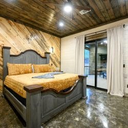 Bed with a gray carved headboard and gold velvet bedspread, with a glass door to the patio