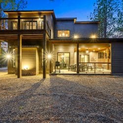 Lit covered patio at night with a gas grill and a dining table