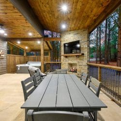 Patio table in front of the stone outdoor fireplace and TV