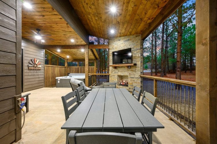 Patio table in front of the stone outdoor fireplace and TV