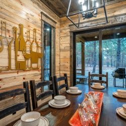 Dining area beside tall windows looking out to the porch and pines