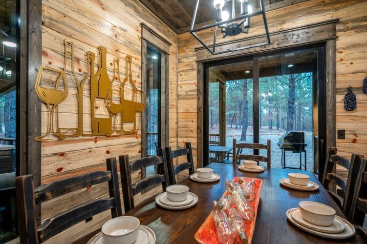 Dining area beside tall windows looking out to the porch and pines