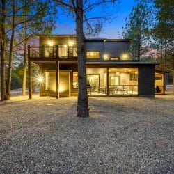 Back of the cabin at night with the lit covered patio, table and grill