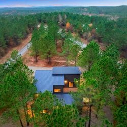 Aerial view of the metal roof with the wooded lot behind it
