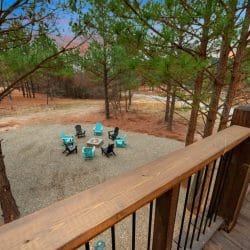 Fire pit on gravel surrounded by teal and black Adirondack chairs