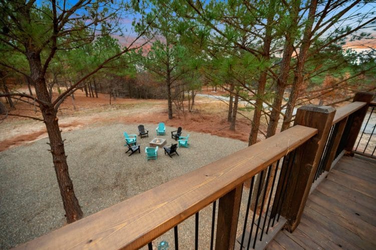Fire pit on gravel surrounded by teal and black Adirondack chairs