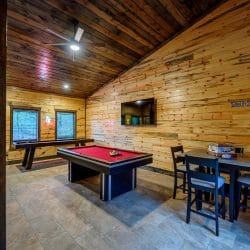 Pool table, a wall-mounted TV and a corner table in the bunk room game area