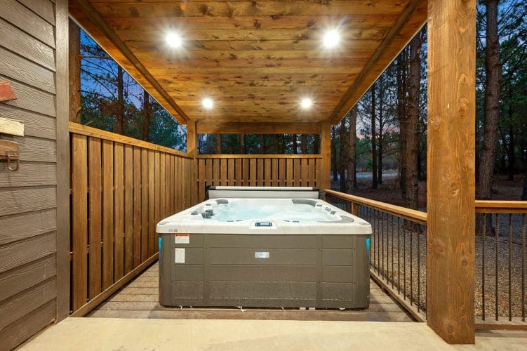 Hot tub with its cover rolled back behind a wooden privacy screen