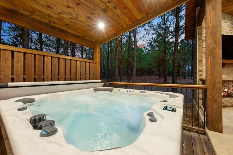 Hot tub with jets beside a wooden fence and trees