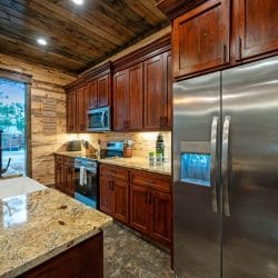 Stainless refrigerator with an ice dispenser beside the range and granite counter