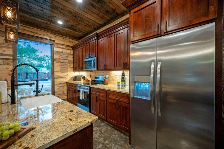 Stainless refrigerator with an ice dispenser beside the range and granite counter