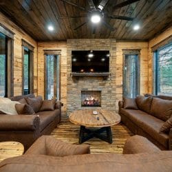 Fireplace with a TV over the wood mantel and a round wood coffee table