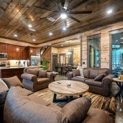 Leather chairs and couch in the living area with the dining table and staircase beyond