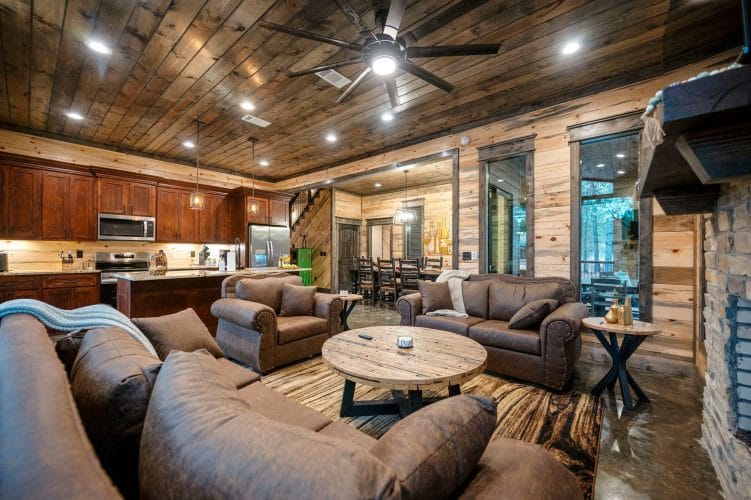 Leather chairs and couch in the living area with the dining table and staircase beyond