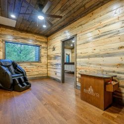 Open loft with hardwood floors and a doorway to a bedroom with a white headboard