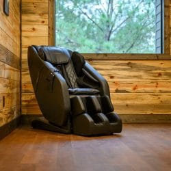 Black massage chair against a wood wall