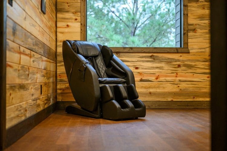 Black massage chair against a wood wall