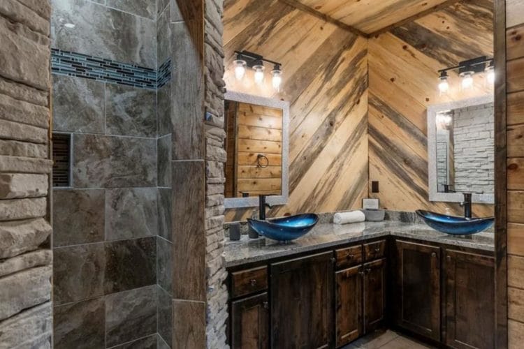Double vanity with blue vessel sinks next to a tiled walk-in shower