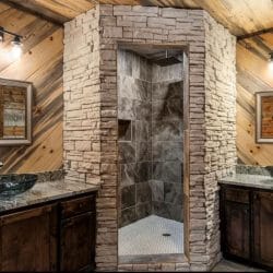 Double vanity with dark vessel sinks and a stone-walled walk-in shower