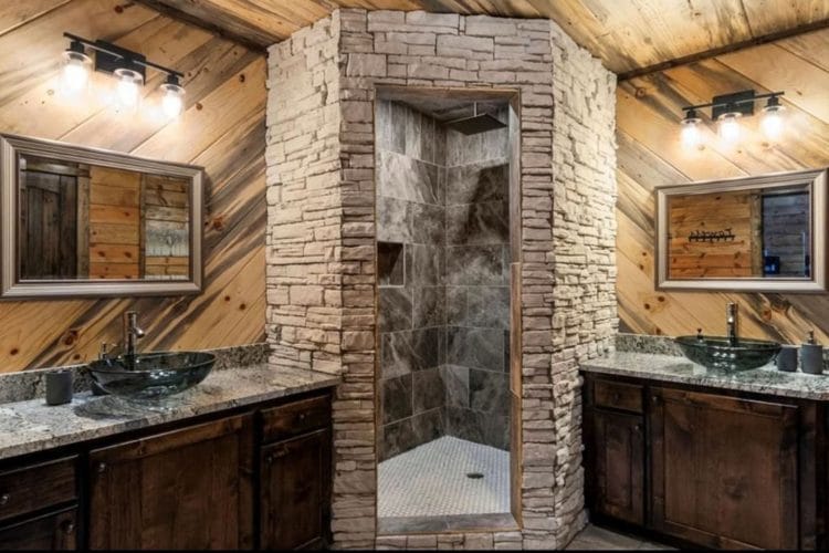 Double vanity with dark vessel sinks and a stone-walled walk-in shower