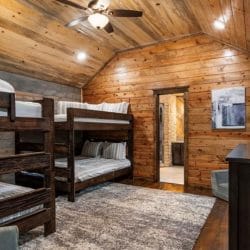 Bunk room with two sets of stacked queen beds, a TV and a doorway to a bathroom
