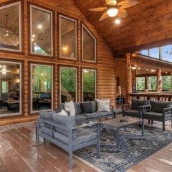 Covered deck with a gray seating group on a rug facing the big front windows