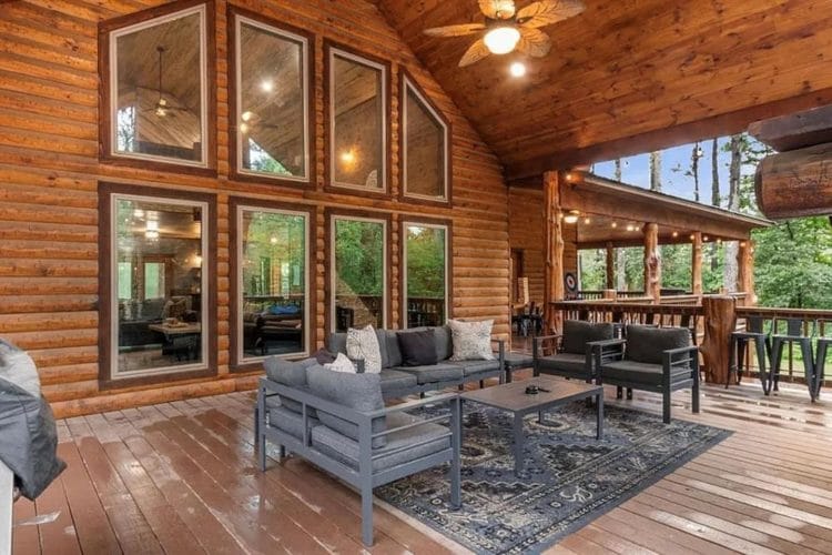 Covered deck with a gray seating group on a rug facing the big front windows
