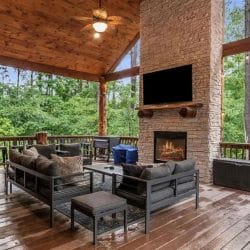 Deck seating around a stone fireplace with a mounted TV