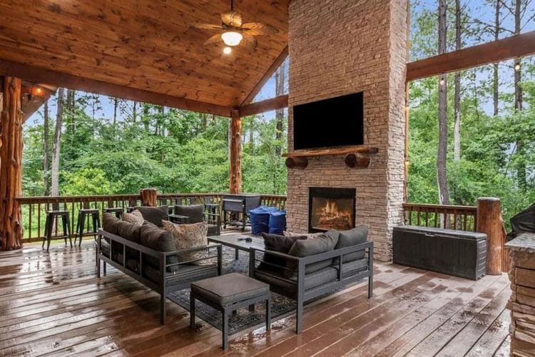 Deck seating around a stone fireplace with a mounted TV