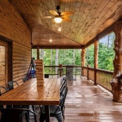 Long wood table with black chairs on the covered deck