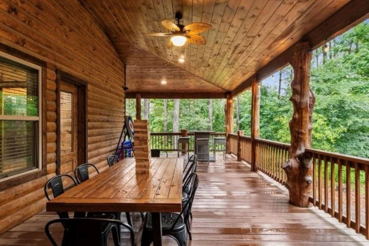 Long wood table with black chairs on the covered deck
