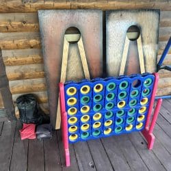 Giant Connect Four game and cornhole boards leaning against the wall on the deck