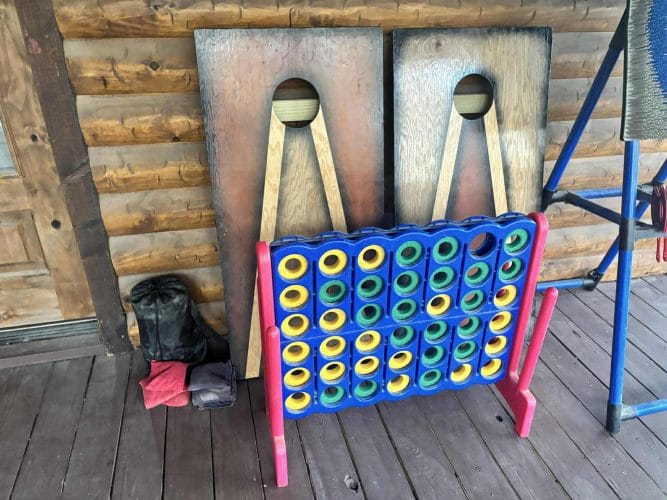Giant Connect Four game and cornhole boards leaning against the wall on the deck
